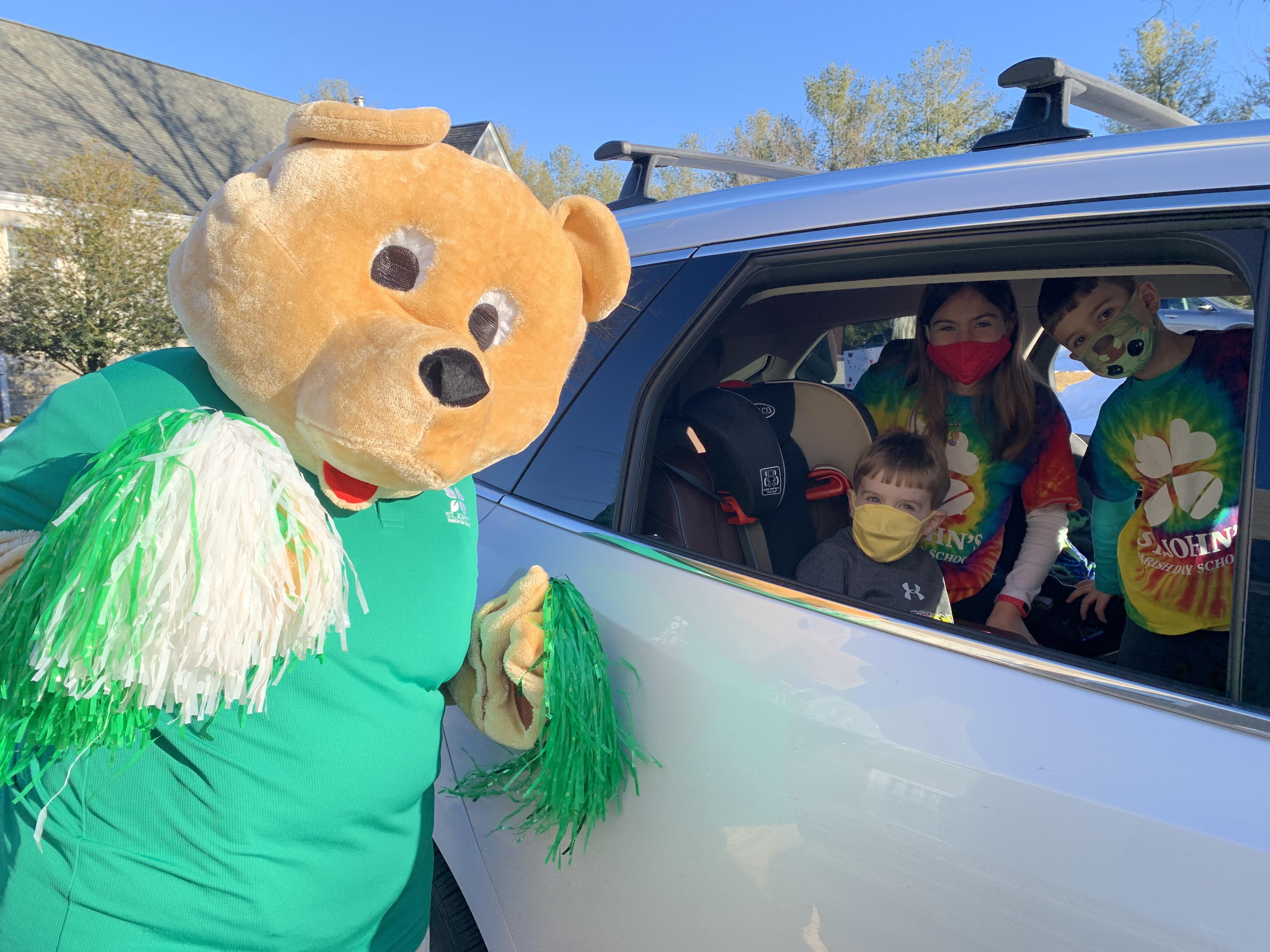 students posing for a picture with spirit bear mascot from inside their car