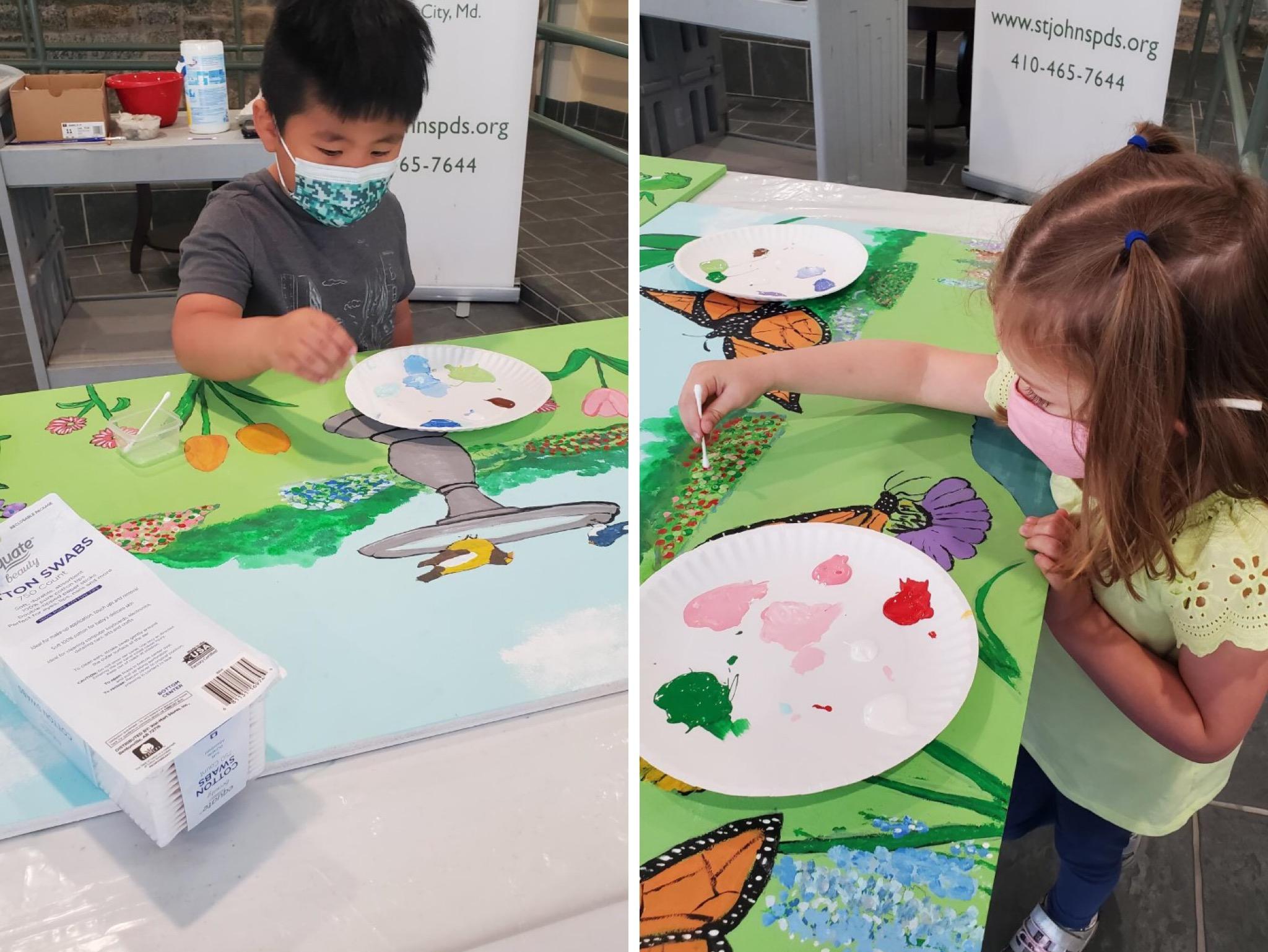 two preschool children painting the mural with cotton swabs