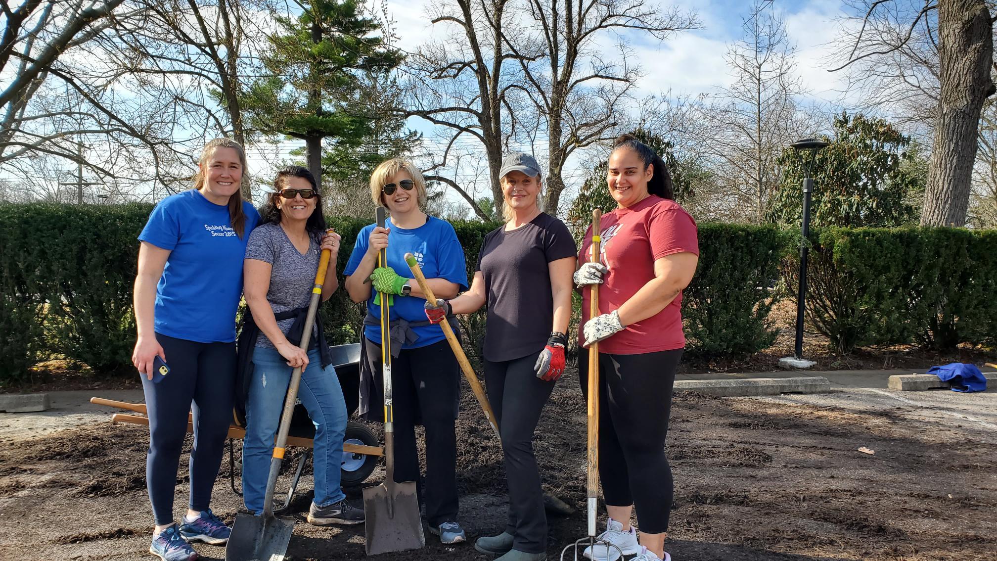 five female staff posing with their campus cleanup tools